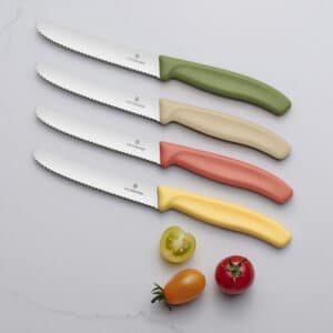 Alle 4 Messerfarben der Swiss Classic Limited Spring-Summer Kollektion auf einem Tisch mit angeschnittenen Tomaten